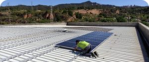 Trabajador instalando placas solares en una nave industrial